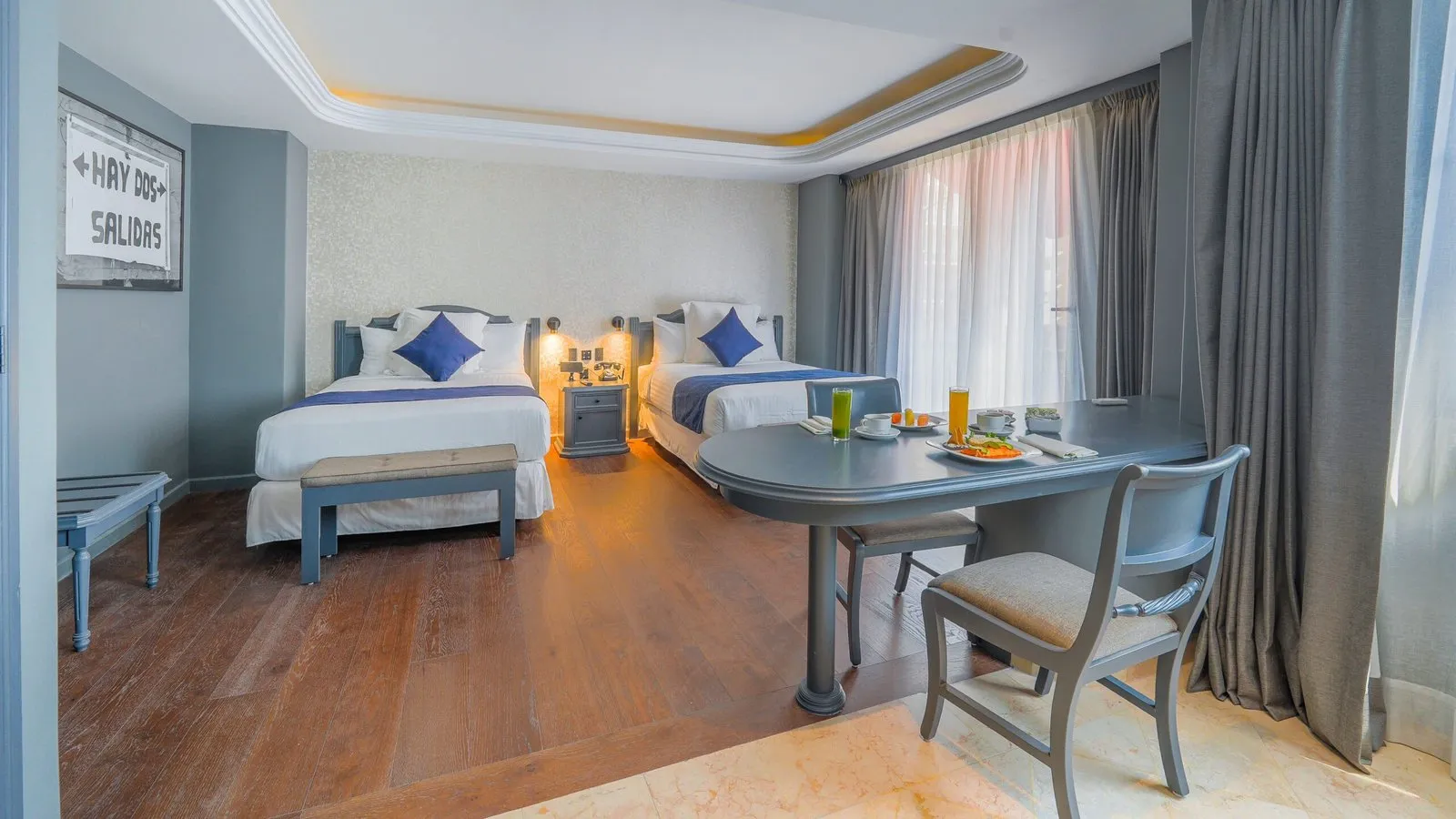 Habitación del hotel con dos camas, un espacio amplio y un desayuno servido sobre la mesa, ofreciendo un ambiente cómodo y acogedor.