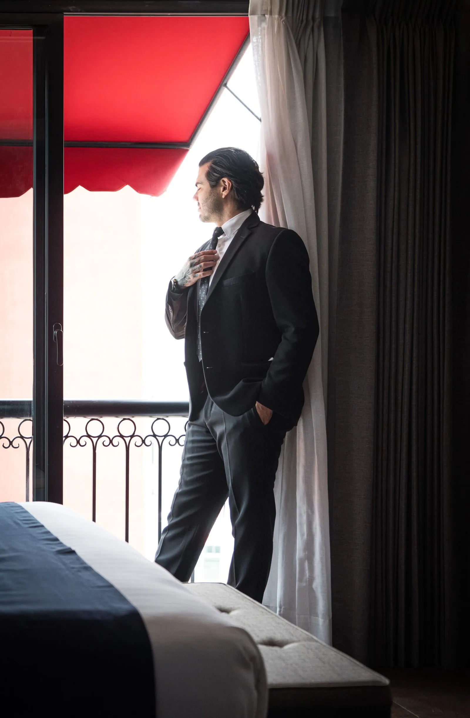 Modelo masculino elegantemente vestido, mirando el paisaje desde la ventana de una habitación del hotel en la Ciudad de México.
