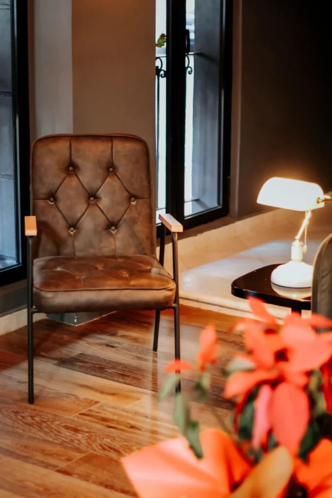 Lobby del Hotel Hive CDMX con una silla elegante, lámpara moderna y flores decorativas.